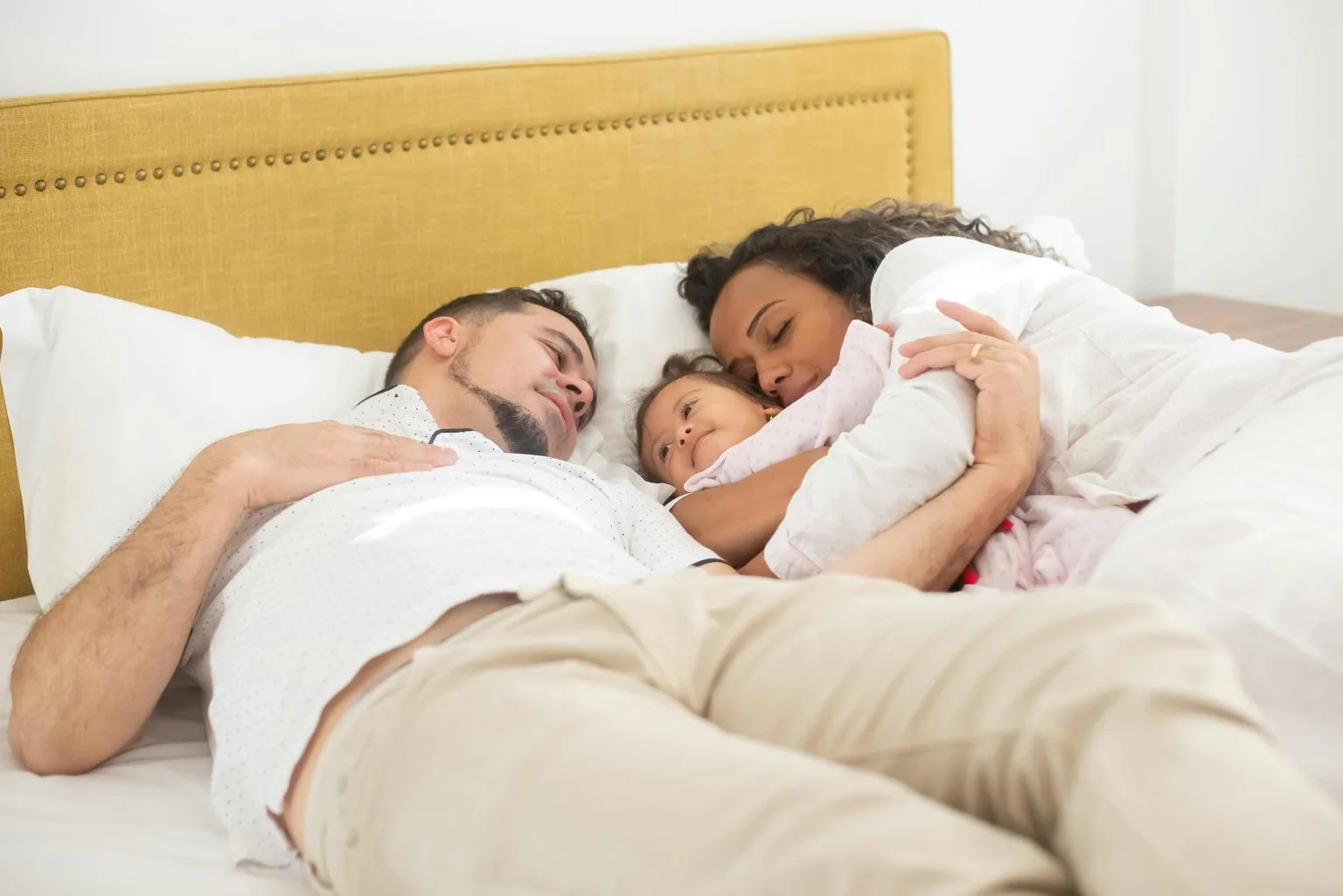 A family of three enjoying a peaceful morning cuddle in bed, highlighting sexual connection after kids.