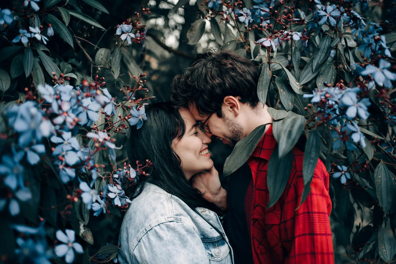 Happy couple sharing a romantic moment surrounded by beautiful blue flowers, practicing mindfulness techniques for desire to reconnect and feel closer.