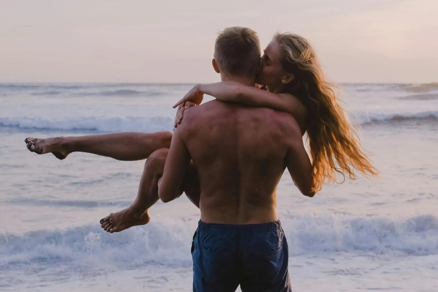 Romantic couple embracing at sunset on a beach, enjoying intimacy and connection, illustrating holistic approaches to improving libido.