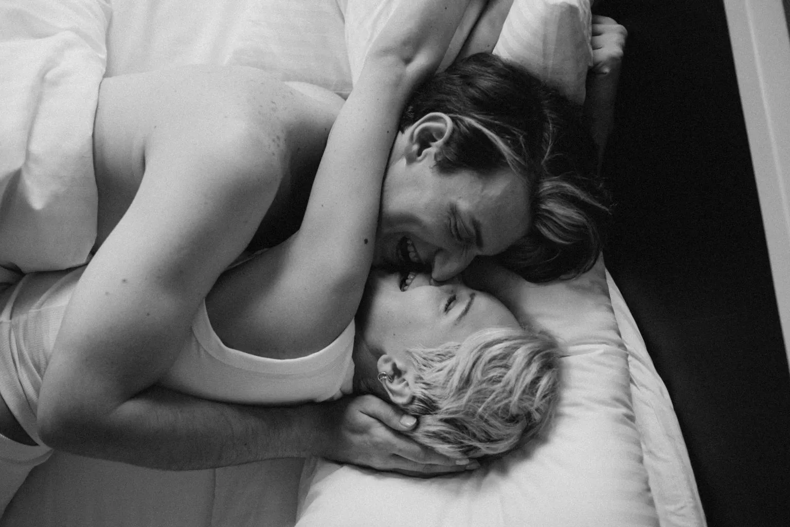 A happy couple hugging in bed, showing how communication styles affect arousal in women by building intimacy and emotional connection