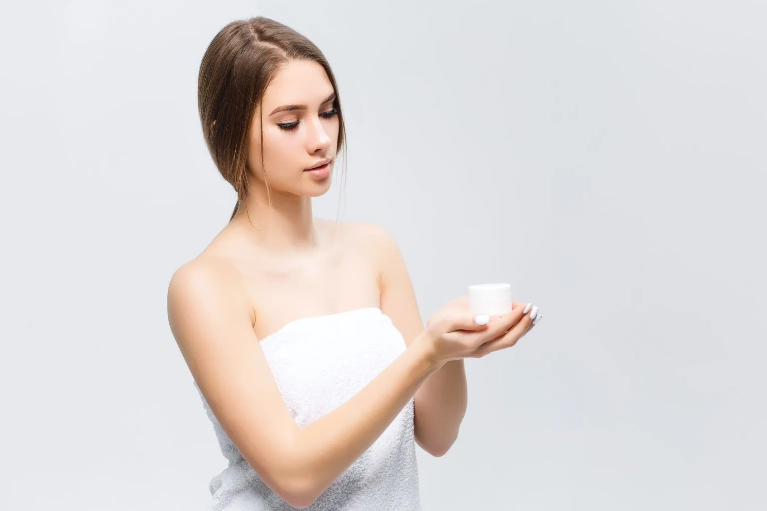 Beauty portrait of a half-naked woman holding cream on her palm, symbolizing gentle skincare and the use of a hypoallergenic lubricant for sensitive female skin.